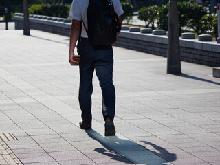 夏の朝の通勤時間で街を渡るひとりの男性サラリーマンの姿