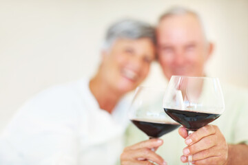 Old couple, glasses and hands for toast in home, marriage anniversary and growth in partnership. Elderly people, romance and cheers with red wine for love celebration, milestone and bonding on date