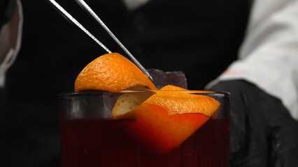 Macrography, skilled hands of a bartender decorate a Negroni cocktail, adorned with a vibrant...