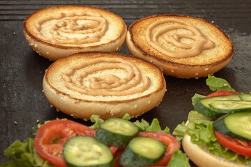 Fried buns with mayonnaise, vegetables and a meat patty - the ingredients for burgers on a street stall. Close-up