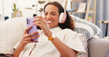 Sofa, happy woman and smartphone with headphone for music, audio track and change playlist in...