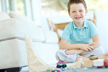 Portrait, cars and confident kid in home playing for learning, development and fun with smile. Excited, boy and proud child enjoying games with toys for childhood hobby or growth at house in England