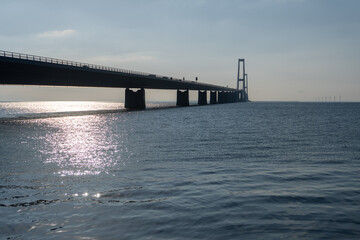 Obraz premium A bridge spans a body of water, with the sun reflecting off the water