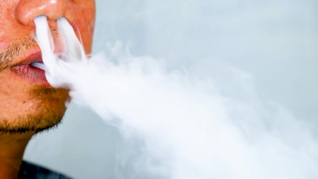 a man with a thin mustache and beard is inhaling and exhaling vapor from an electronic cigarette or vape