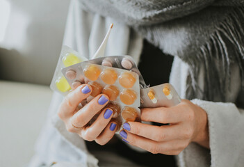 a woman wrapped in a scarf holds a lot of pills for illness against the background of medicines