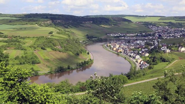 View from Grevenmacher vineyards in Luxembourg onto landscape with Moselle River and the towns of Machtum and Nittel on a sunny day, camera panning right