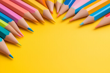 Naklejka premium Colorful pencils arranged on a bright yellow background showcasing artistic tools for creativity