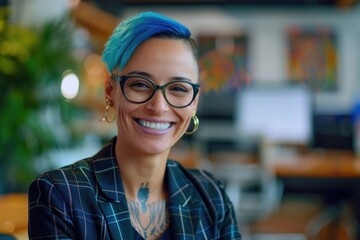 A woman with bright blue hair and glasses smiling at the camera