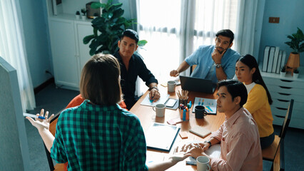 Top view of manager standing and present idea at whiteboard. Group of diverse people listen presentation while raising hand for asking question. Team looking at leader talking about plan. Convocation.