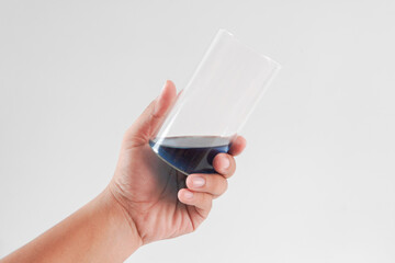 A glass of dark liquid is sitting on a white background