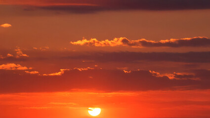 Fototapeta premium Vibrant red sunset with orange clouds and setting sun