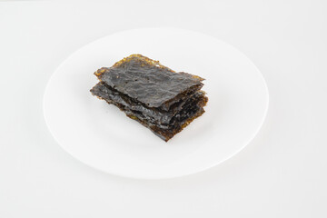 A plate of seaweed snacks sits on a white table