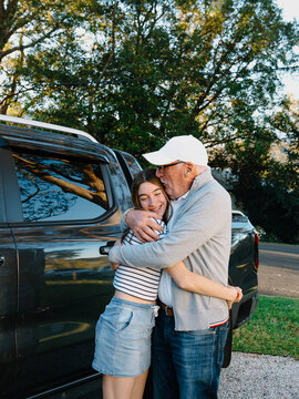 Grandfather embracing granddaughter outside the house.