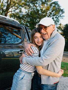 Grandfather embracing granddaughter outside the house.