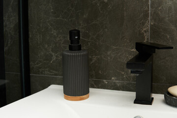 A sleek black soap dispenser with a textured finish and a wooden base