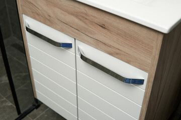 A modern bathroom vanity with a white cabinet and a wood-grain countertop