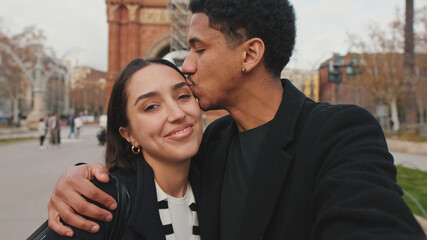 Happy couple taking selfie with city park and historical buildings in background