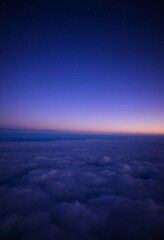 Fototapeta premium Deep Blue and Purple Sky with Fluffy Clouds Stretching to the Horizon Under a Blanket of Stars