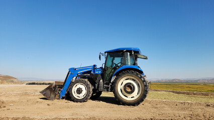 Obraz premium A tractor pressing corn leaves to make corn silage on a reinforced concrete silage pit to make winter dairy cattle roughage