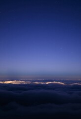 Night Sky Blending Softly into Blue and Purple with Stars Shining Over Waves of Clouds