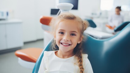 Fototapeta premium young girl is sitting in a dentist's chair with a pink headrest. She is smiling and she is enjoying her visit to the dentist