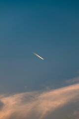 The contrail of an airplane in the sky at dusk.