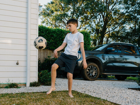 Young boy playing soccer outside in yard