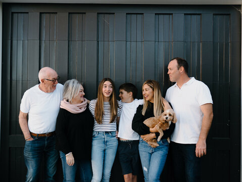 Multigenerational family standing outside in front of black garage door
