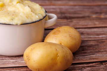 Whipped Mashed Potatoes Surrounded by Whole Potatoes on a Vintage Wooden Table