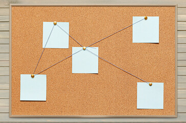 Blank paper notes are pinned to a cork board. The concept of detective investigation or training ....
