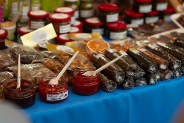 Counter with farm products. Dried fruits, handmade sweets on table of street store. Jar of homemade red jam. Translation from Georgian: Pepper jam. Tbilisi city holiday Tbilisoba. Food festivale. Fair