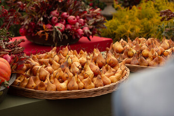 Horizontal photo. Yellow ripe fresh juicy tasty pears on straw tray at street fair. Counter with farm products on Tbilisoba fall city holiday. Food festival. Concept of harvest day, healthy eat, lunch
