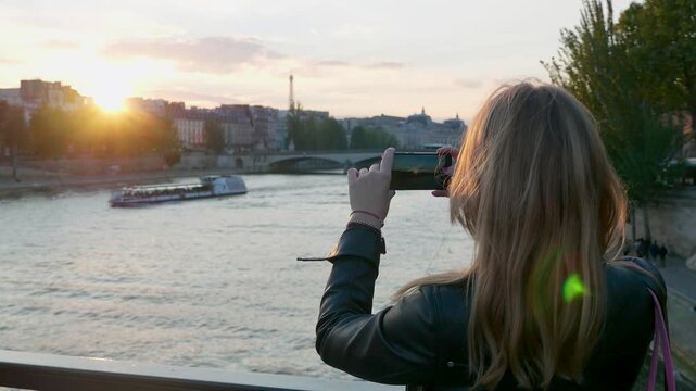 Young female taking a video of Paris at sunset