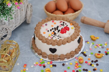 Cake with cherry on top and eggs on a marble background.