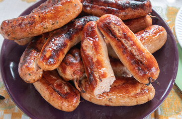 Grilled barbecue sausages on a plate, top view, close-up