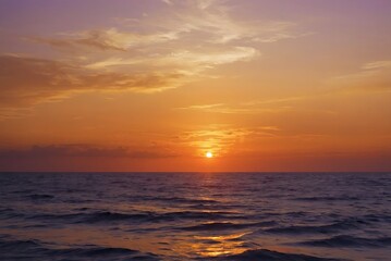 Obraz premium A stunning sunset casts vibrant colors over the calm sea, creating a picturesque evening scene.