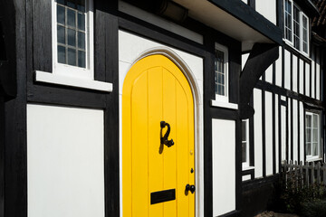 Bright yellow front door seen on a very old, timber built English home in the east of England. The...