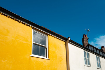Contrasty yellow painted semi detached house seen in bright daylight.