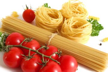 On a white background lie spaghetti and macaroni in the form of a nest with vegetables