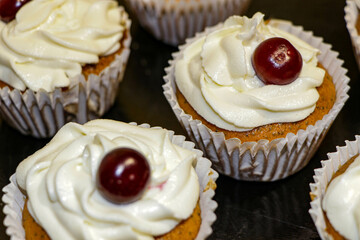 A golden-brown cupcake, warm from the oven, topped with a glistening red cherry