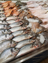 Food background close-up. There are many varieties of fresh fish on the ice lying in a row. Sale of fresh frozen fish at the fish market