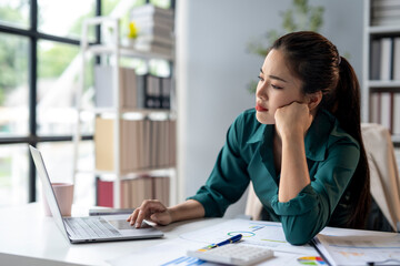 A woman is sitting at a desk with a laptop open in front of her