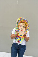 Woman holding colorful mask covering face at carnival celebration