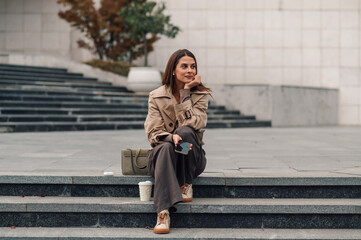 Businesswoman taking break on stairs holding smartphone