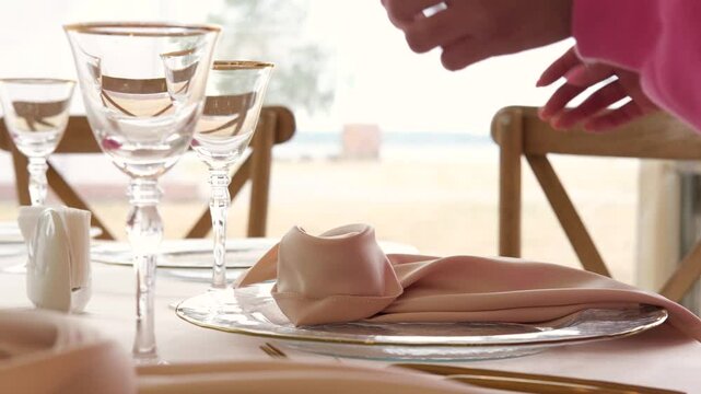 Waitress in pink sweater folding napkin on plate at fully served table in slow motion