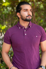 Close-up portrait of a confident, handsome, bearded Asian-Indian man with a ponytail. He's gazing...