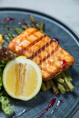 Grilled salmon fillet served with asparagus and lemon on plate