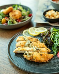 Breaded chicken breast with lemon and salad on restaurant table