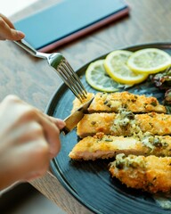 Hands cutting breaded pork cutlets with a metal knife