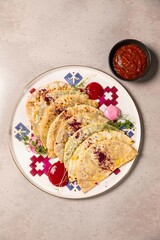 Delicious flatbreads with filling served on plate with sauces